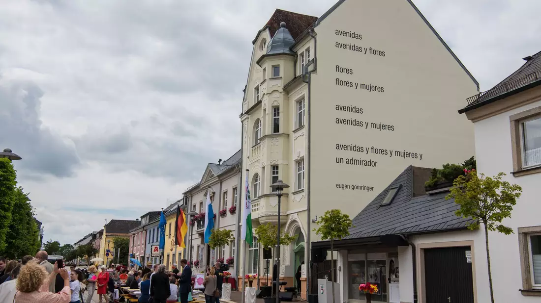 Eugen Gomringers Gedicht «avenidas» ist an einer Rehauser Hausfassade zu lesen. (Archivbild) - Bild: Nicolas Armer/dpa