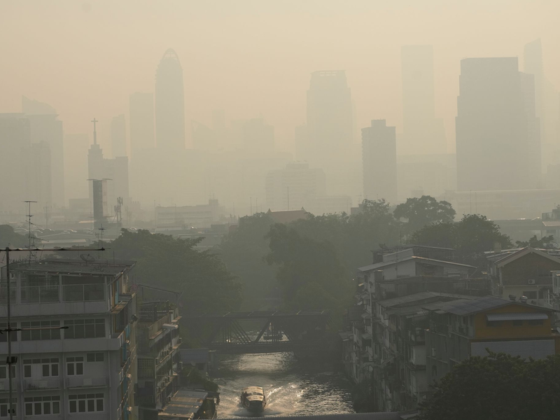 Pendler tragen Gesichtsmasken, um sich vor der Luftverschmutzung zu schützen. - Foto: Sakchai Lalit/AP/dpa