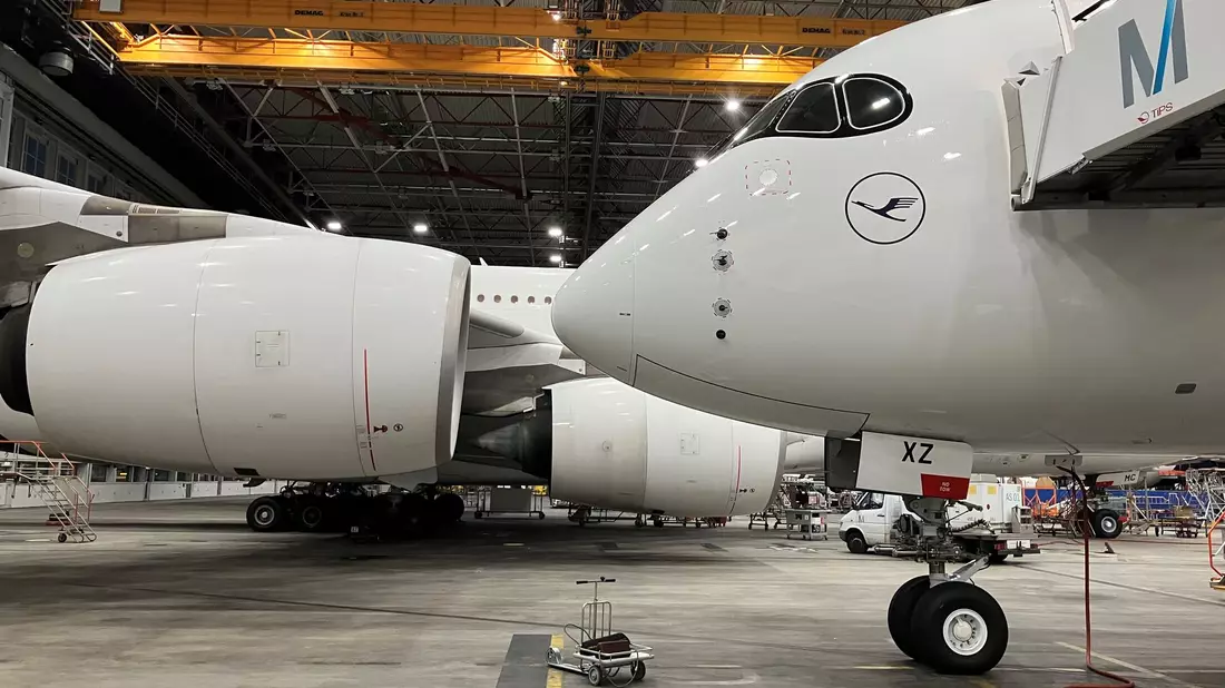 Der neueste Airbus A 350/900 der Lufthansa steht kurz vor seinem kommerziellen Erstflug im riesigen Wartungshangar der Lufthansa am Münchner Flughafen. Im Hintergrund steht ein Airbus A380. - Bild: Carsten Hoefer/dpa
