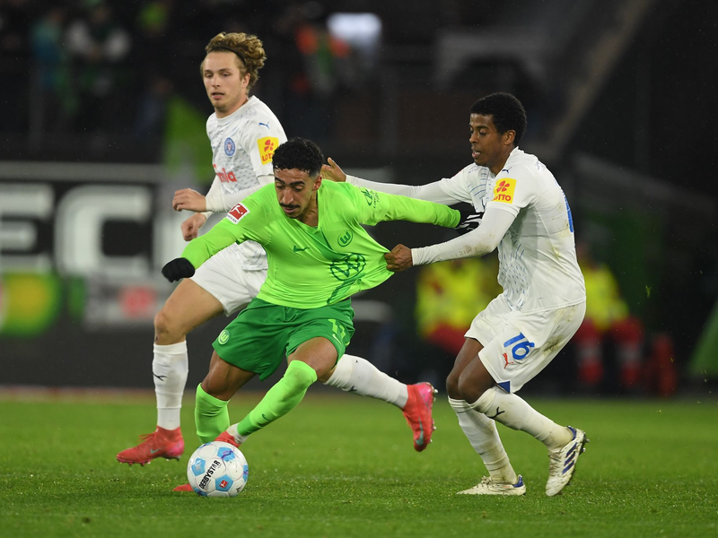 Wolfsburgs Mohamed Amoura (r) spielt gegen Kiels David Zec. - Foto: Swen Pförtner/dpa