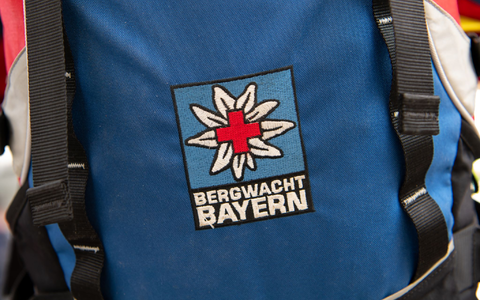Das Logo der Bergwacht ist an einem Rucksack zu sehen. Bei Oberstdorf musste die Bergwacht nun einen Mann retten, der ohne richtige Ausrüstung und Erfahrung zwei Nächte in den Bergen verbrachte. (Archivfoto-Illustration) - Foto: Sven Hoppe/dpa