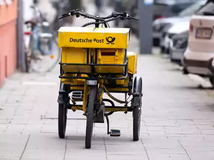 Ein Fahrrad eines Briefträgers steht auf einem Gehweg - auch dieser Briefträger möchte vermutlich gern deutlich besser bezahlt werden. - Foto: Sven Hoppe/dpa