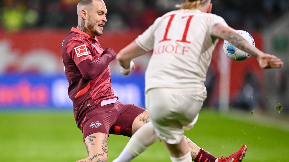 Augsburgs Torwart Finn Dahmen kauert bedröppelt am Boden, die Leipziger Assan Quedraogo (M) und Christoph Baumgartner (r) bejubeln das 0:5.  - Foto: Harry Langer/dpa