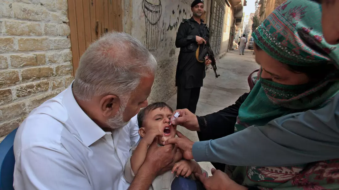 Impf-Teams in Pakistan werden von bewaffneten Männern bewacht, weil sie oft Ziel von Anschlägen sind. (Archivbild) - Bild: Mohammad Sajjad/AP/dpa