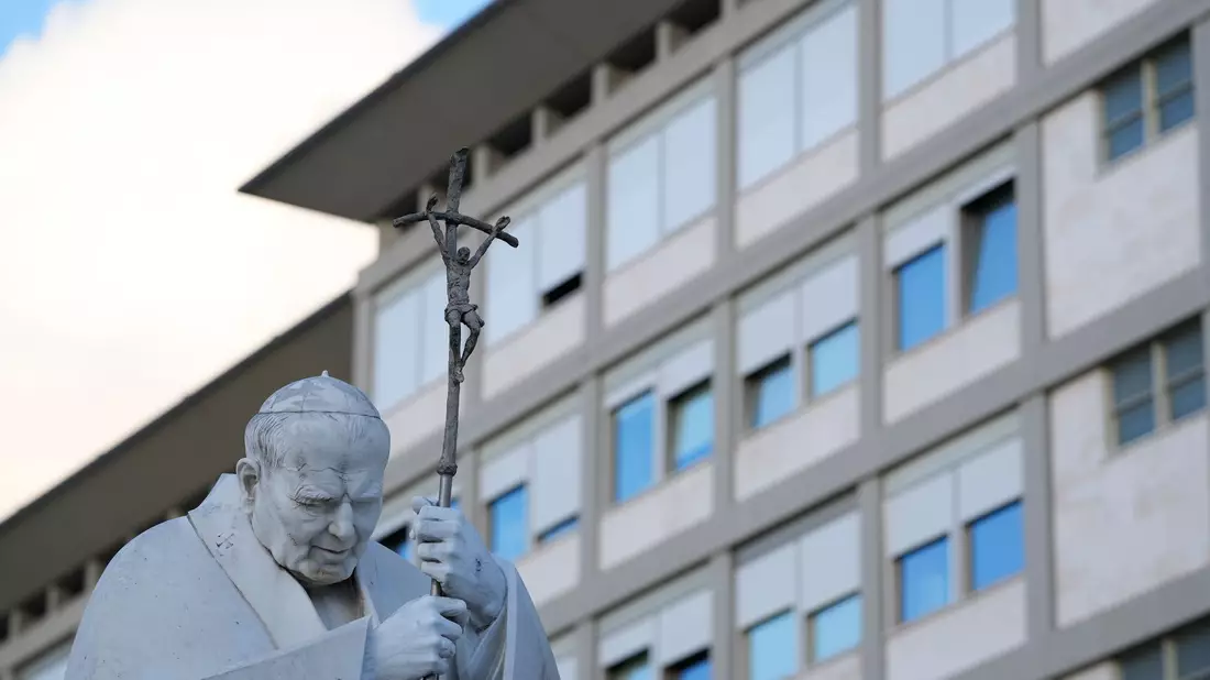 Eine Statue von Papst Johannes Paul II. steht auf dem Vorplatz der Gemelli-Klinik. - Bild: Andrew Medichini/AP/dpa