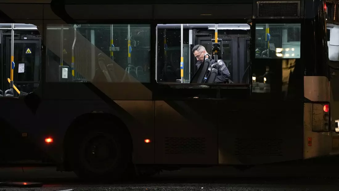 Ein Polizeibeamter inspiziert einen Bus.  - Bild: Ohad Zwigenberg/AP/dpa