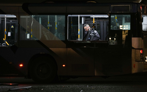 Ein Polizeibeamter inspiziert einen Bus.  - Foto: Ohad Zwigenberg/AP/dpa