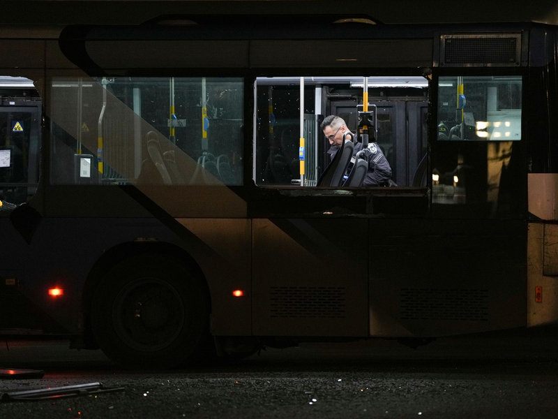 Ein Polizeibeamter inspiziert einen Bus.  - Foto: Ohad Zwigenberg/AP/dpa