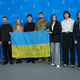 Das Team des Films «Strichka chasu» mit einer ukrainischen Flagge, auf der die Lehrerkollegen des Protagonisten und jetzigen Soldaten Borys Khovriak (M) unterschrieben haben.  - Foto: Soeren Stache/dpa