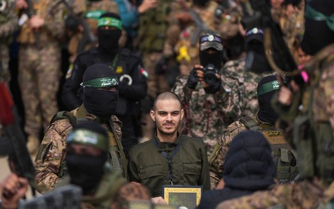 Ein vermummter Hamas-Kämpfer gibt einer israelischen Geisel Anweisungen während einer Übergabe-Veranstaltung im Gazastreifen. - Foto: Abdel Kareem Hana/AP/dpa