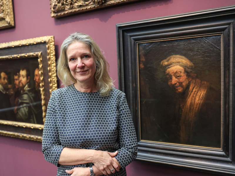 Anja Sevcik steht zwischen einem Selbstbildnis von Peter Paul Rubens unter Freunden (links) und einem Selbstbildnis von Rembrandt (rechts).  - Foto: Oliver Berg/dpa