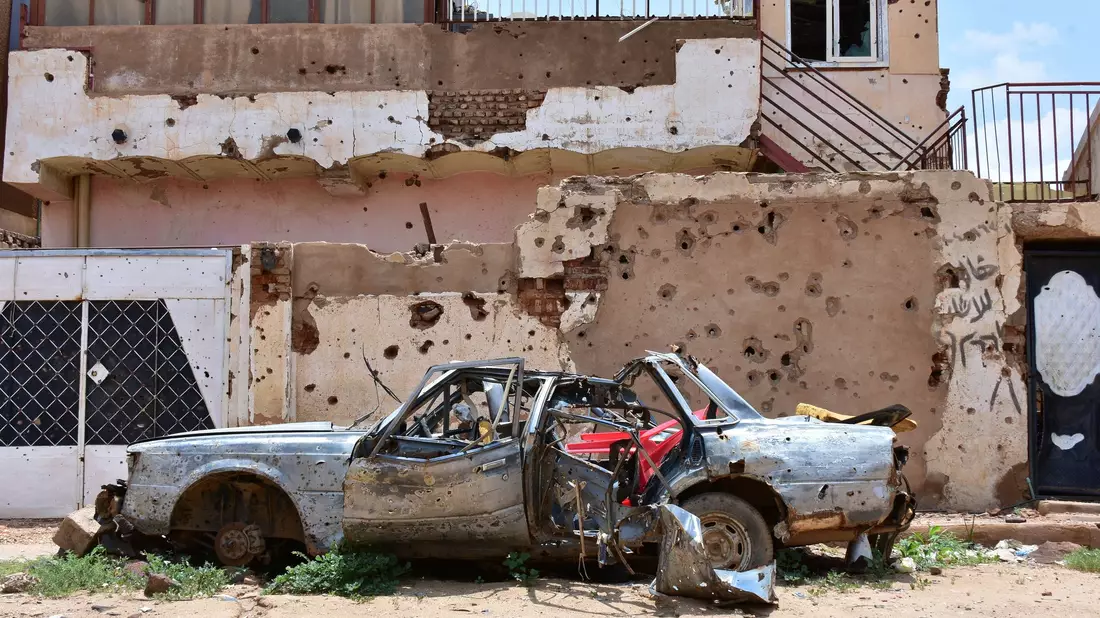 Ein zerstörtes Auto steht im sudanesischen Omdurman vor einem Haus voller Einschüsse. (Archivbild) - Bild: Mudathir Hameed/dpa