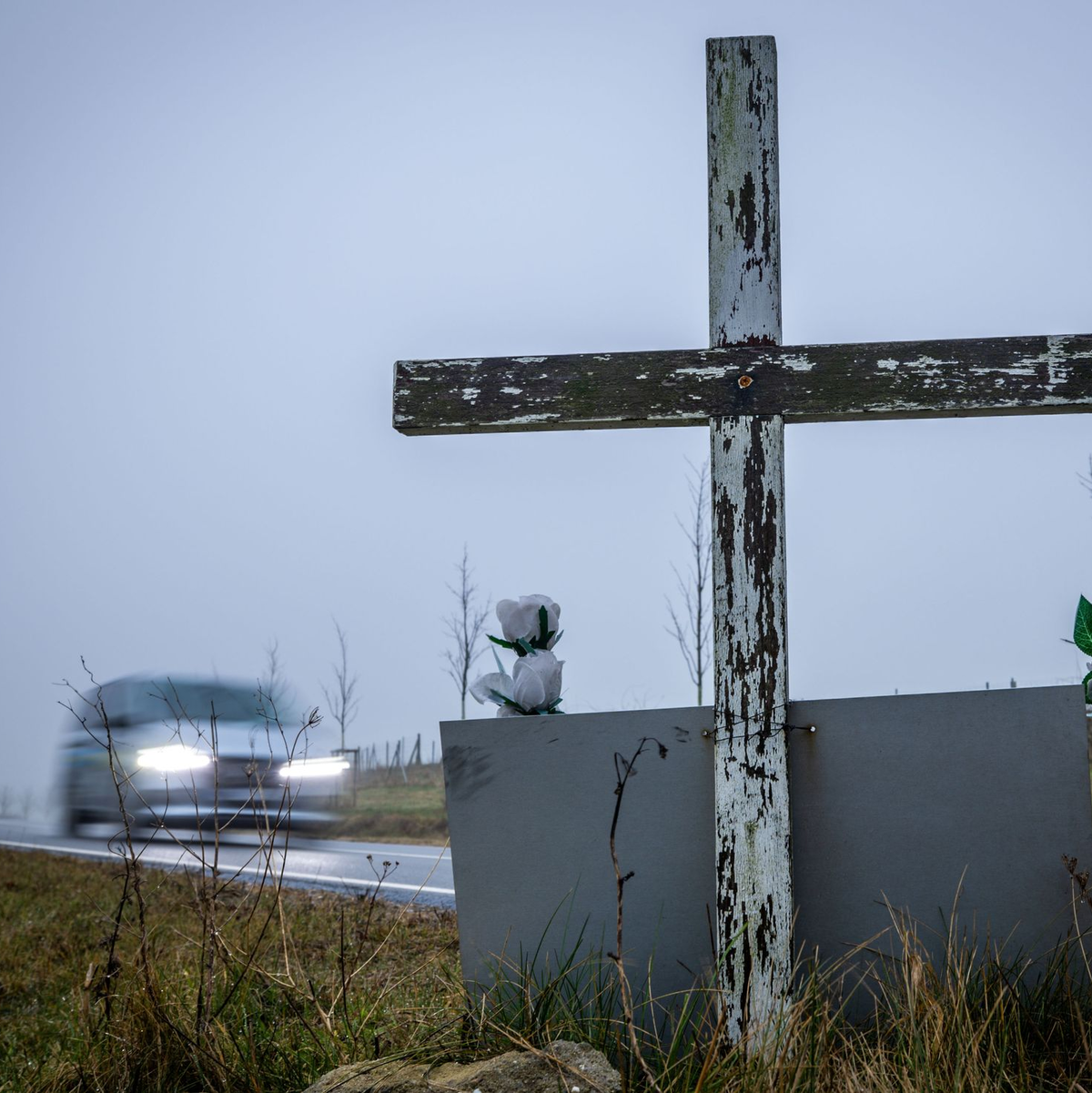 in Auto fährt auf einer Landstraße an einem hölzernen Kreuz vorbei, welches zur Erinnerung an ein Unfallopfer aufgestellt wurde. - Foto: Jens Büttner/dpa