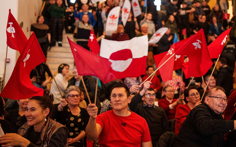 Grönländer schwenken während einer TV-Debatte diverse Flaggen. - Foto: Evgeniy Maloletka/AP/dpa
