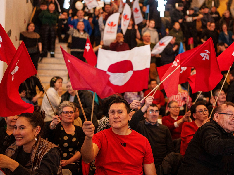 Grönländer schwenken während einer TV-Debatte diverse Flaggen. - Foto: Evgeniy Maloletka/AP/dpa