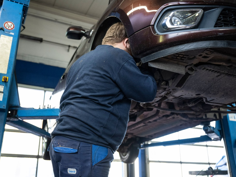 Ein Mechaniker schaut in einer Kfz-Werkstatt in den Radkasten eines Autos. - Foto: Hannes P. Albert/dpa