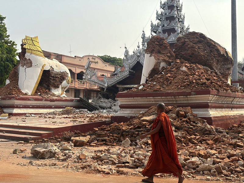 Ein buddhistischer Mönch geht in der Nähe einer eingestürzten Pagode nach einem Erdbeben in Mandalay.  - Foto: Thein Zaw/AP/dpa