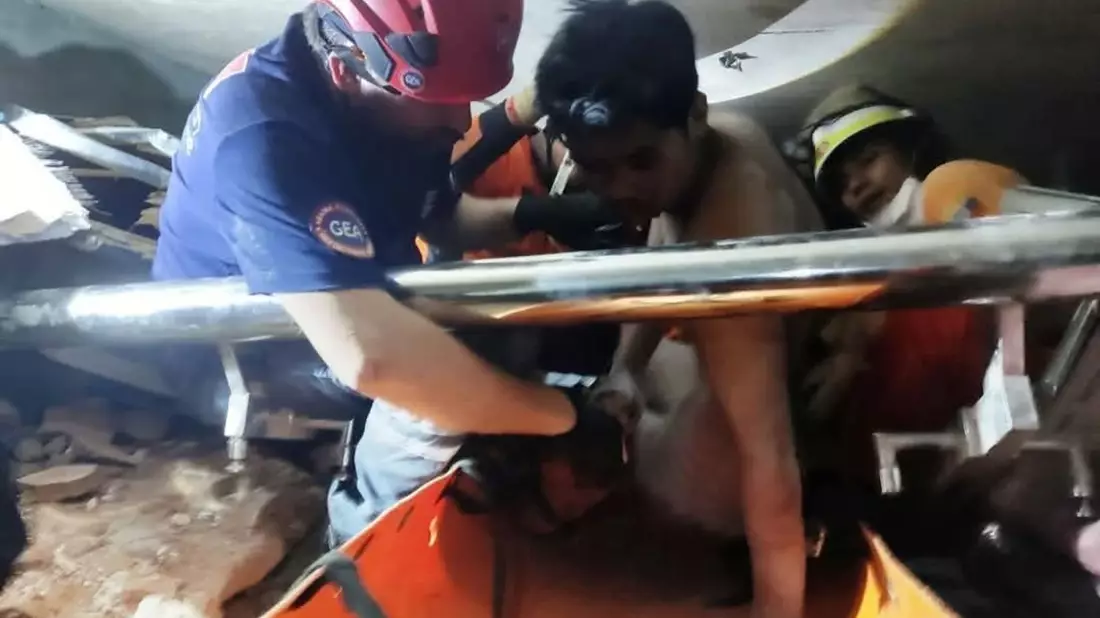 Ein junger Mann wurde wie durch ein Wunder lebend in den Trümmern gefunden. - Bild: Myanmar Fire Services Department/XinHua/dpa