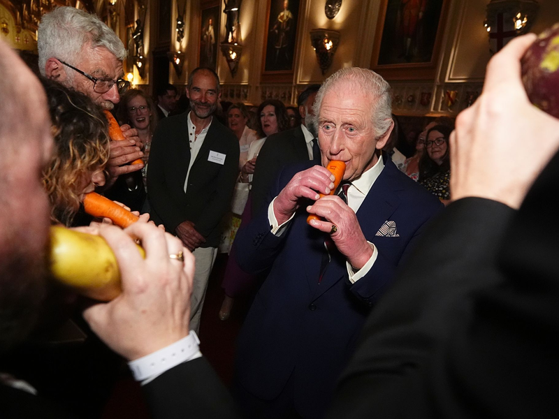 König Charles III. versuchte sich an der Karottenflöte. - Foto: Aaron Chown/PA Pool/AP/dpa