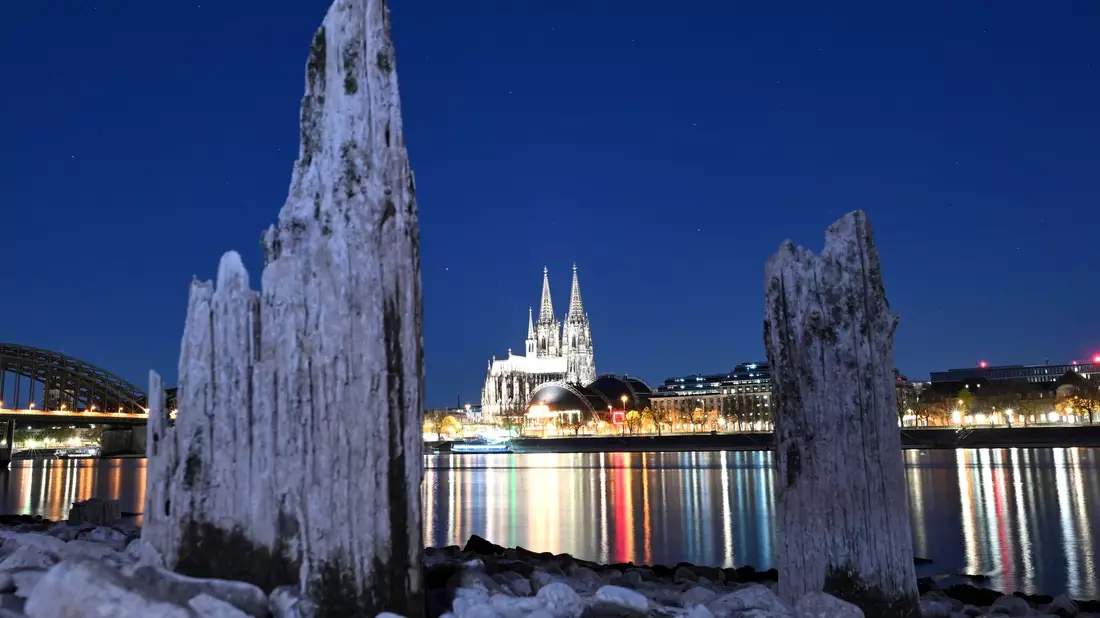 Teile einer Holzkonstruktion, die normalerweise unter Wasser liegen, sind am Rhein gegenüber vom Kölner Dom zu sehen.  - Bild: Federico Gambarini/dpa