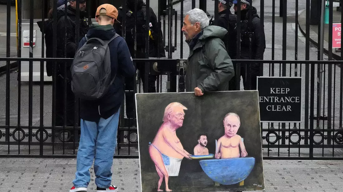 Ein Künstler geht in London mit einem Gemälde von Trump, Selenskyj und Putin am Tag der Ukraine-Gespräche vor den Toren der Downing Street 10 entlang.  - Bild: Frank Augstein/AP/dpa