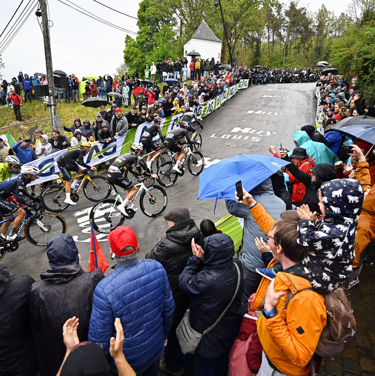 Olympiasieger Remco Evenepoel (M) mit goldenem Helm an der Mauer von Huy. Rechts neben ihm Tadej Pogacar. - Foto: Jasper Jacobs/Belga/dpa