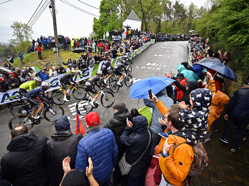 Olympiasieger Remco Evenepoel (M) mit goldenem Helm an der Mauer von Huy. Rechts neben ihm Tadej Pogacar. - Foto: Jasper Jacobs/Belga/dpa
