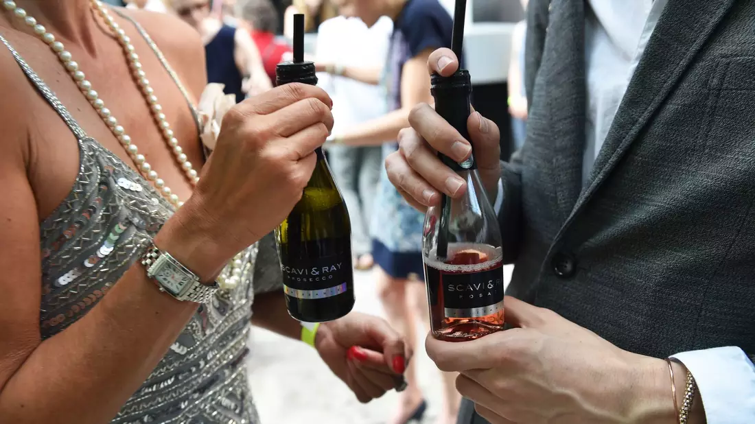 Small Talk mit Prosecco: Gäste unterhalten sich am Rande einer Modenschau in Berlin. (Archivbild) - Bild: picture alliance / ZB