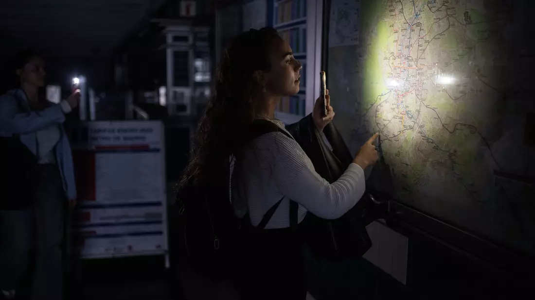 Eine Frau behilft sich mit der Taschenlampe ihres Handys, um den Plan des Madrider U-Bahn-Netzes anschauen zu können. - Bild: Alejandro Martínez Vélez/EUROPA PRESS/dpa