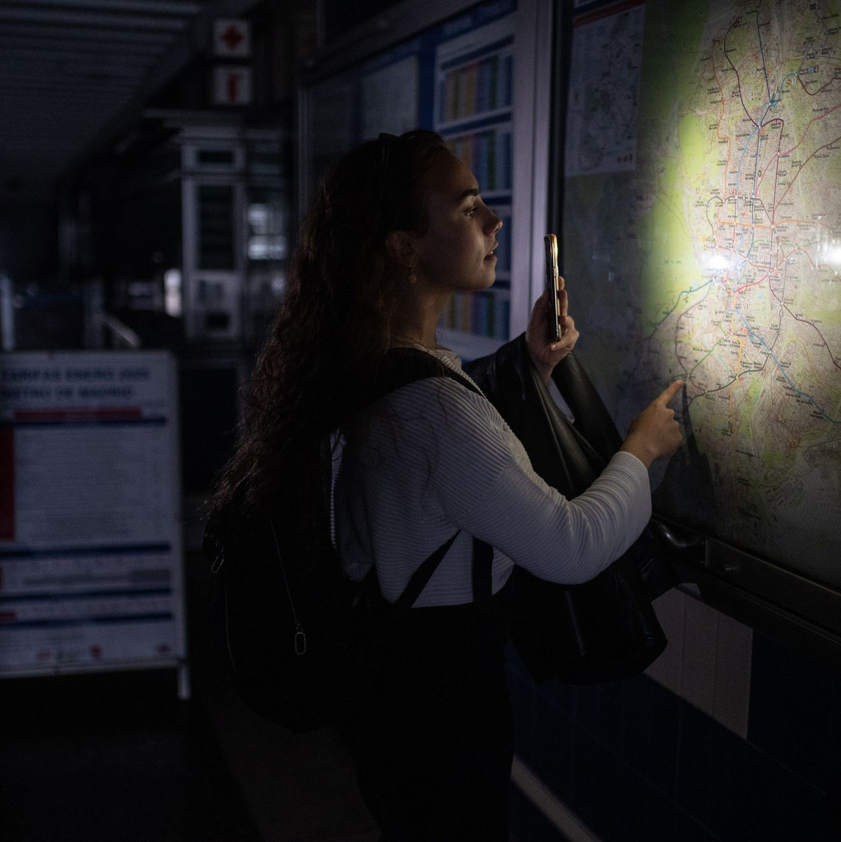 Eine Frau behilft sich mit der Taschenlampe ihres Handys, um den Plan des Madrider U-Bahn-Netzes anschauen zu können. - Foto: Alejandro Martínez Vélez/EUROPA PRESS/dpa