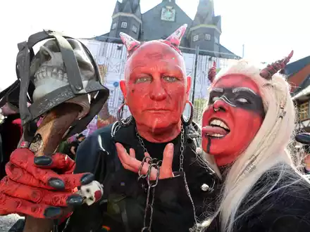 Im Teufelskostüm stehen Besucher auf dem Marktplatz in Wernigerode.  - Foto: Matthias Bein/dpa