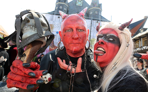 Im Teufelskostüm stehen Besucher auf dem Marktplatz in Wernigerode.  - Foto: Matthias Bein/dpa