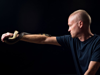 Der von Schlangen begeisterte US-Amerikaner Tim Friede hat sich selbst immer größere Dosierungen von Schlangengiften verabreicht und kann nun einfach so eine Wasserkobra auf dem Arm tragen.  - Foto: ---/Centivax/dpa