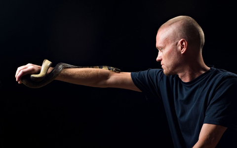 Der von Schlangen begeisterte US-Amerikaner Tim Friede hat sich selbst immer größere Dosierungen von Schlangengiften verabreicht und kann nun einfach so eine Wasserkobra auf dem Arm tragen.  - Foto: ---/Centivax/dpa