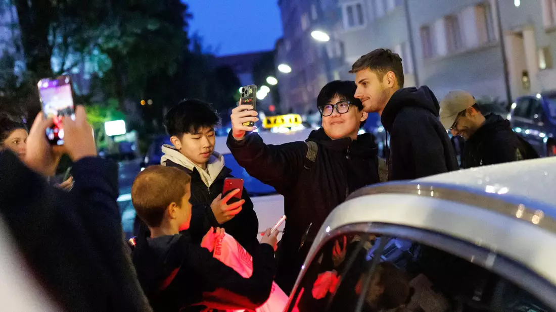 Torhüter Jonas Urbig schreibt Autogramme, bevor er mit seinen Teamkollegen feiert.  - Bild: Matthias Balk/dpa