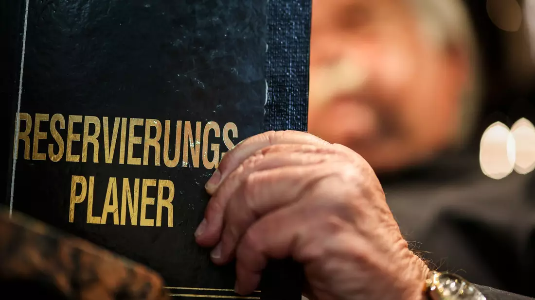 Altmodisch? Ein Gastronom schaut in sein Reservierungsbuch. - Bild: Christoph Reichwein/dpa