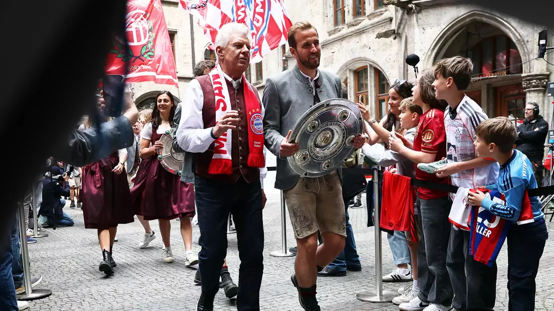Bundesliga-Torschützenkönig Harry Kane trägt die Meisterschale flankiert von Oberbürgermeister Dieter Reiter (mit Fanschal) ins Münchner Rathaus. - Bild: Daniel Löb/dpa