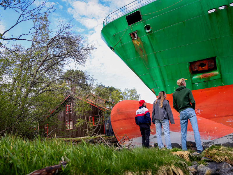 Ein Containerschiff ist in Norwegen kurz vor einem Haus am Wasser zum Stehen gekommen. - Foto: Jan Langhaug/NTB/dpa