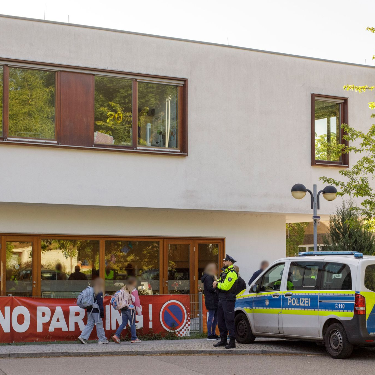 Die Polizei steht vor einer Grundschule im Berliner Bezirk Spandau, während Schüler am Morgen zur Schule kommen.  - Foto: Julius-Christian Schreiner/dpa