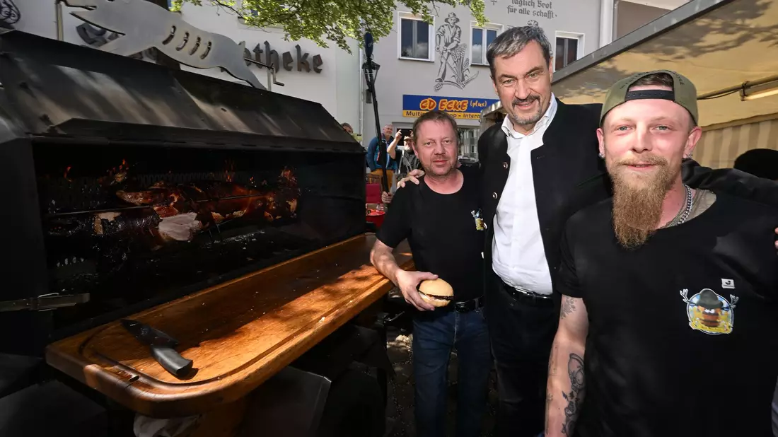 Ministerpräsident Söder am Schweinegrill.  - Bild: Felix Hörhager/dpa