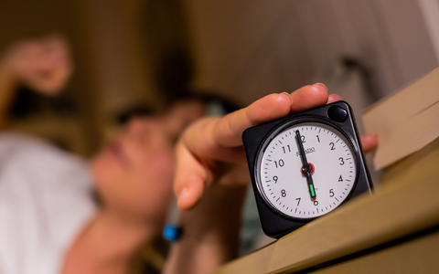Eine Frau schaltet vom Bett aus einen auf sechs Uhr gestellten Wecker aus. - Foto: Christoph Soeder/dpa Eine Frau schaltet vom Bett aus einen auf sechs Uhr gestellten Wecker aus. - Foto: Christoph Soeder/dpa