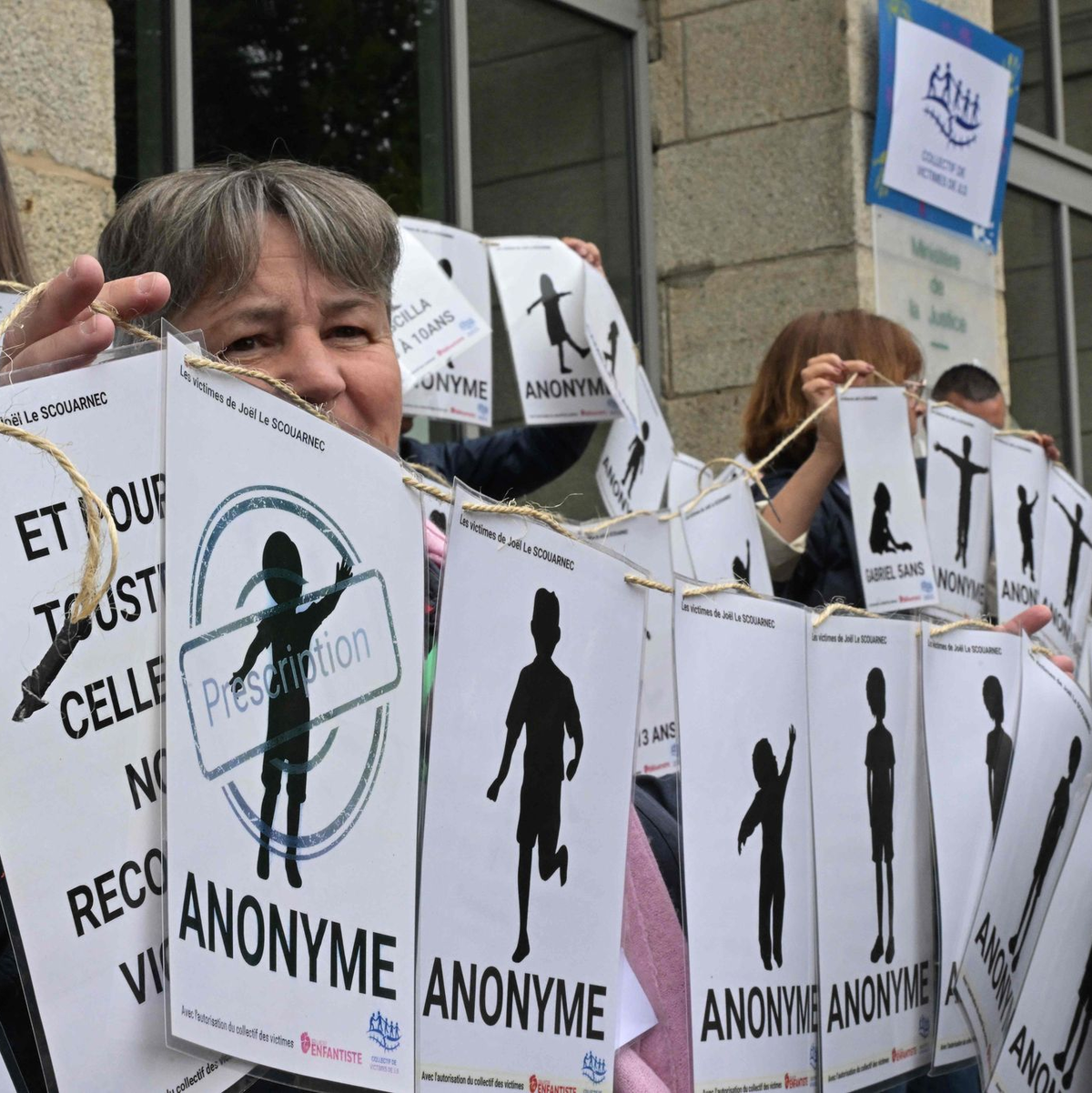 Demonstranten halten vor dem Gerichtsgebäude Schilder mit den Namen der Opfer. - Foto: Damien Meyer/AFP/dpa