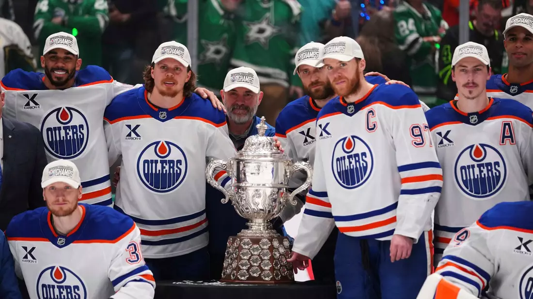 Leon Draisaitl posiert hinter Kapitän Connor McDavid mit dem Pokal für den Sieger der Western Conference. - Bild: Julio Cortez/AP/dpa