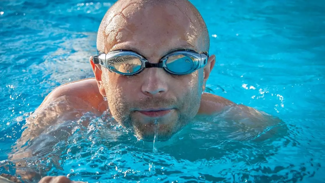Mann schwimmt mit einer Schwimmbrille in einem Pool.  - Bild: Pixabay@jarmoluk
