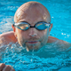 Mann schwimmt mit einer Schwimmbrille in einem Pool.  - Foto: Pixabay@jarmoluk