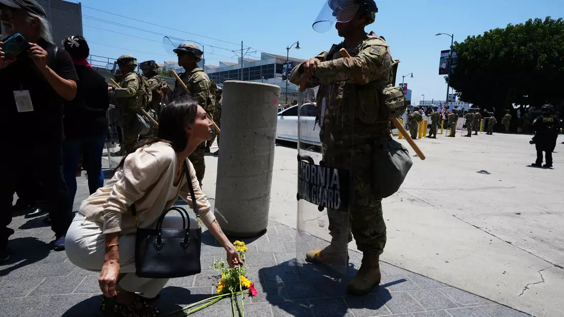 Eine Frau legt Blumen vor der Nationalgarde nieder.  - Bild: Damian Dovarganes/AP/dpa