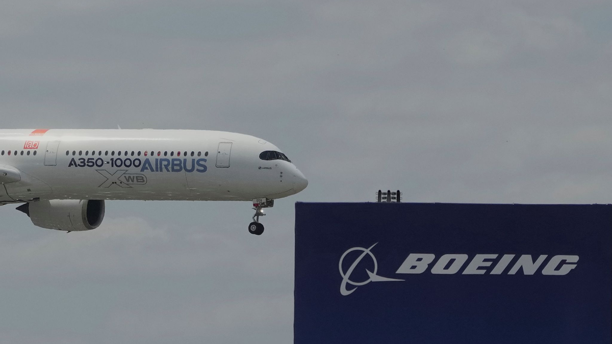 Die zwei großen Konkurrenten: Ein Airbus fliegt bei einer Vorführung auf der Luftfahrtmesse Salon du Bourget an einem Logo von Boeing vorbei. - Foto: Michel Euler/AP/dpa