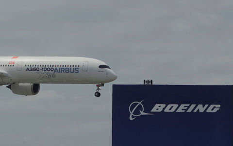 Die zwei großen Konkurrenten: Ein Airbus fliegt bei einer Vorführung auf der Luftfahrtmesse Salon du Bourget an einem Logo von Boeing vorbei. - Foto: Michel Euler/AP/dpa