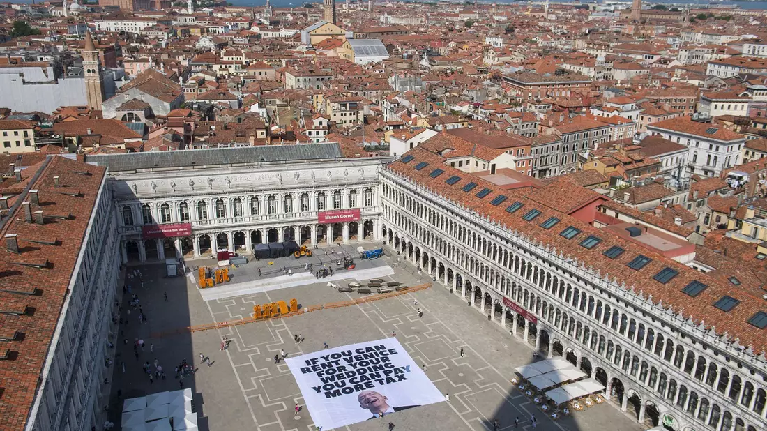 Das Transparent zeigt ein Foto des Amazon-Gründers, auf dem steht: «If you can rent Venice for your wedding you can pay more tax». - Bild: Greenpeace/Greenpeace/AP/dpa