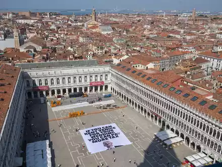 Mit einem Plakat auf dem Markusplatz fordern Greenpeace-Aktivisten, Bezos höher zu besteuern. - Foto: Greenpeace/Greenpeace/AP/dpa
